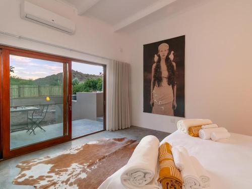 a bedroom with a bed and a painting of a woman at Aardvark Bioreserve in Ladismith