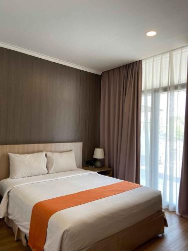 a bedroom with a large bed and a large window at Green Red Hotel Syariah Jombang in Jombang