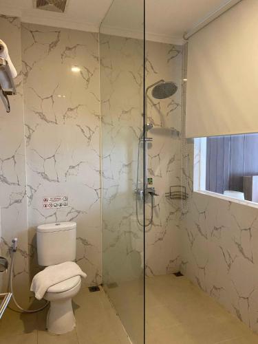 a bathroom with a toilet and a glass shower at Green Red Hotel Syariah Jombang in Jombang
