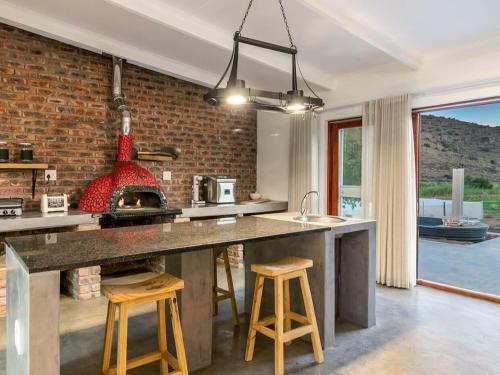 a kitchen with a brick wall and a kitchen island with stools at Aardvark Bioreserve in Ladismith