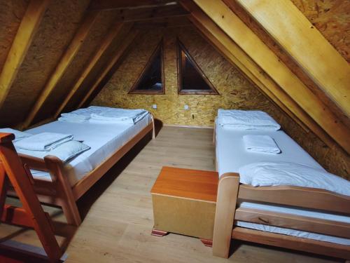 two beds in a attic room with windows at Brvnare Tomić 2 i 3 in Ždrelo
