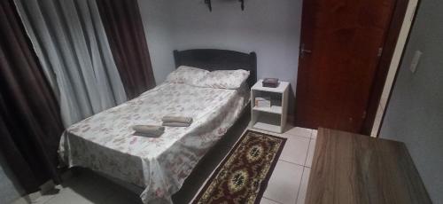 a small bedroom with a bed and a table at Casa 3 quartos com suite e ar condicionado in Patos de Minas