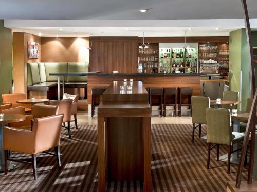 a restaurant with tables and chairs and a bar at Mercure Hotel Saarbrücken Süd in Saarbrücken