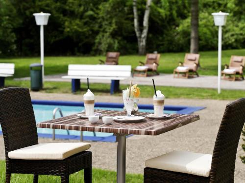 a table with drinks on it next to a pool at Mercure Hotel Saarbrücken Süd in Saarbrücken