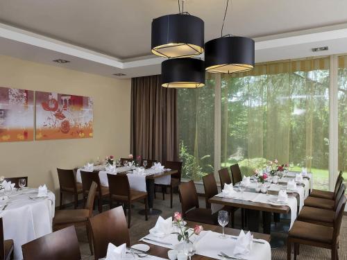 a dining room with tables and chairs and a large window at Mercure Hotel Saarbrücken Süd in Saarbrücken