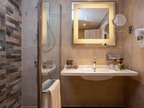 a bathroom with a sink and a mirror and a shower at Novotel Cairo Airport in Cairo