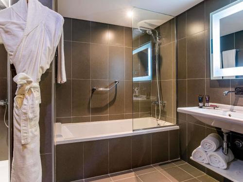 a bathroom with a shower and a tub and a sink at Novotel Cairo Airport in Cairo