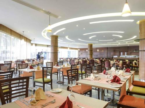 a dining room with tables and chairs in a restaurant at Novotel Cairo Airport in Cairo