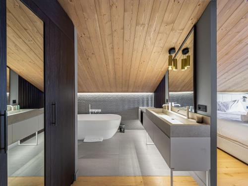 un bagno con due lavandini, una vasca e un letto di Chalet familial moderne à Méribel Village, terrasse sud avec jacuzzi, proche pistes et commerces - FR-1-566-56 a Les Allues