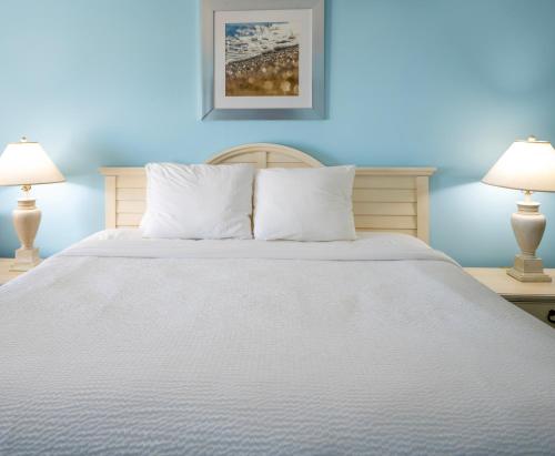 a bedroom with a white bed with two lamps at Drifting Sands Oceanfront Hotel in Ship Bottom