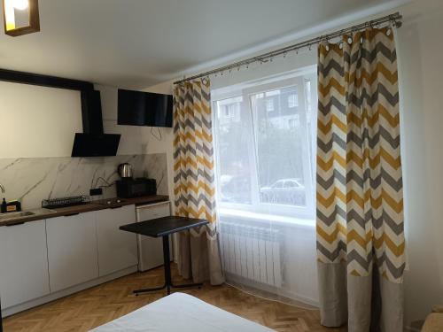 une cuisine avec des rideaux, une table et une fenêtre dans l'établissement Zefir Horynia, à Lviv