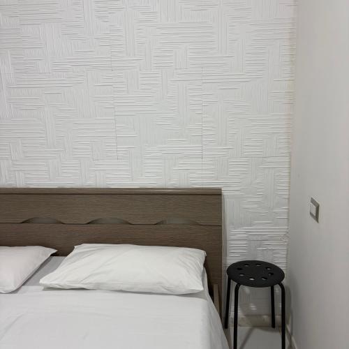 a bedroom with a white bed and a black stool at mono centro storico in Benevento