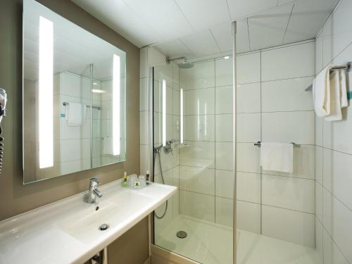 a white bathroom with a sink and a shower at Mercure Angers Centre de Congrès in Angers