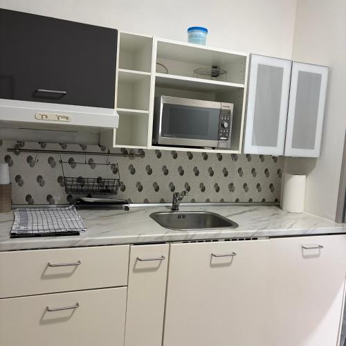 a kitchen with white cabinets and a sink and a microwave at mono centro storico in Benevento