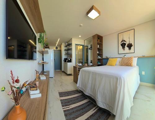 a bedroom with a white bed and a kitchen at DVA Cabedelo by Hosppedar in Cabedelo