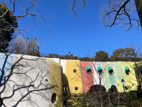 a wall with a colorful building with a tower in the background at Le Cave Troll ル カーブ トロル in Mitaka