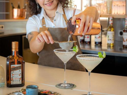 a woman pouring a drink into a martini glass at Mercure La Rochelle Vieux Port in La Rochelle