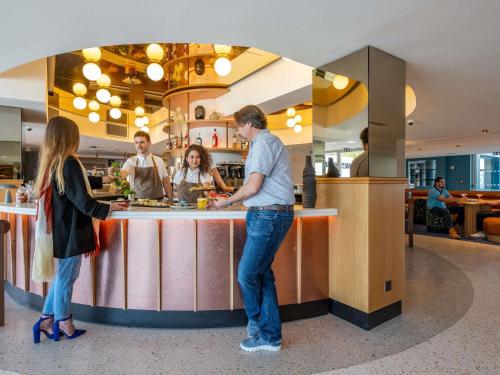 a group of people standing at a counter in a restaurant at Mercure La Rochelle Vieux Port in La Rochelle