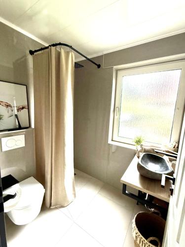 a bathroom with a toilet and a window at Wilhelmines Hafenliebe am Park mit Balkon, Netflix, & Privatparkplatz in Wilhelmshaven
