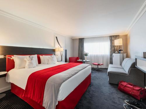 a hotel room with a large bed and a chair at Mercure Paris CDG Airport & Convention in Roissy-en-France