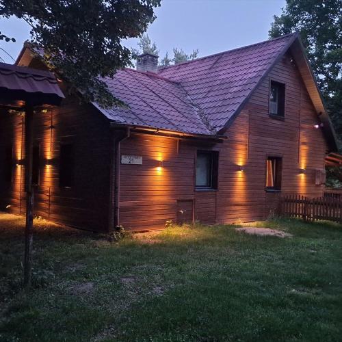 a house with lights on the side of it at Ranczo w lesie - domki z jacuzzi in Ożarów