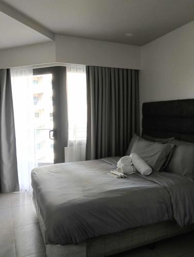 a bedroom with a bed with a teddy bear on it at Tambuli Resort Tower D in Lapu Lapu City