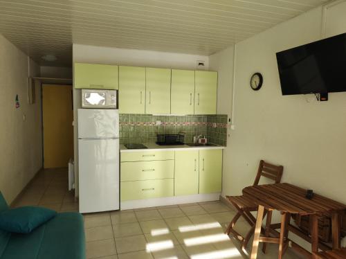 a kitchen with white cabinets and a table and a tv at L'océan, les pins et vous in Lacanau