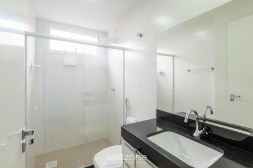 a bathroom with a sink and a toilet and a mirror at Apto c/ 2 Quartos a 400 m da Praia INA1306 in Guarapari