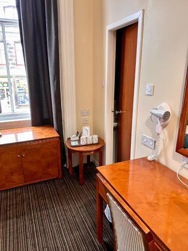 a hotel room with a dresser and a desk and a window at Royal Thurso Hotel in Thurso