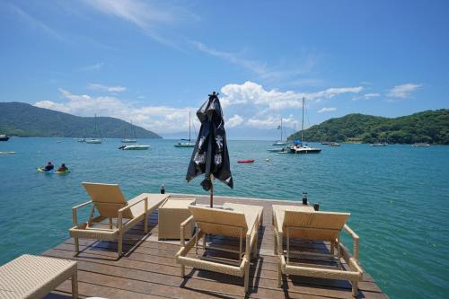 a table with chairs and an umbrella on a dock at CASA DA ILHA INN AND SPA Anexo1 in Angra dos Reis