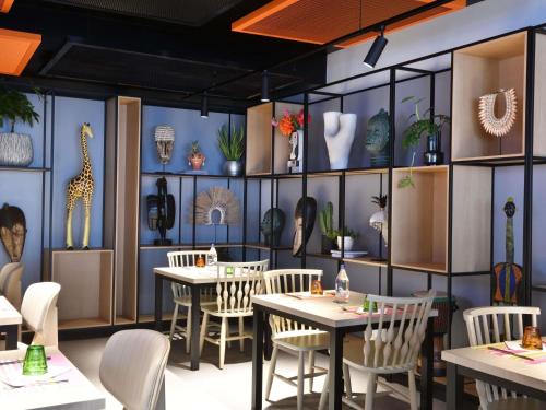 a restaurant with tables and chairs and vases on the wall at Ibis Styles Abidjan Plateau in Abidjan