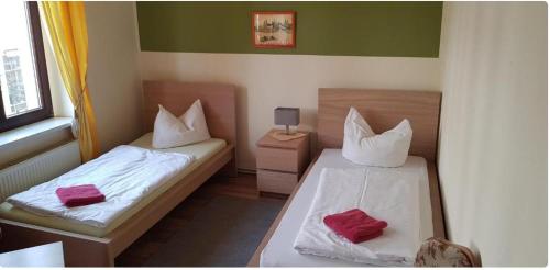two beds in a small room with red pillows at Hotel- Garni zum Löwen in Bad Freienwalde