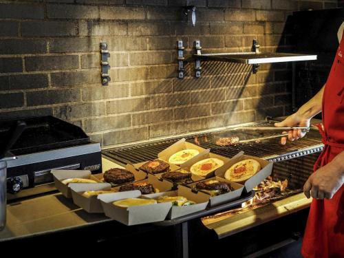 a person is cooking food on a grill at ibis Orange Centre in Orange