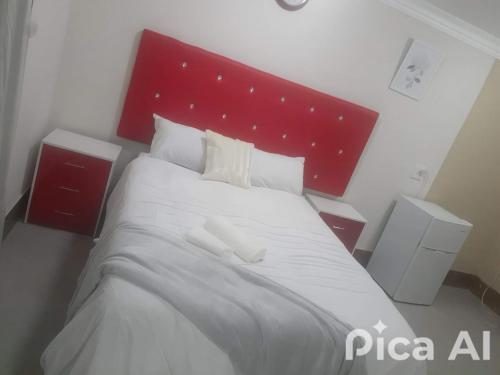 a bedroom with a large white bed with a red headboard at Nelspruit Nice luxury lodge in Nelspruit