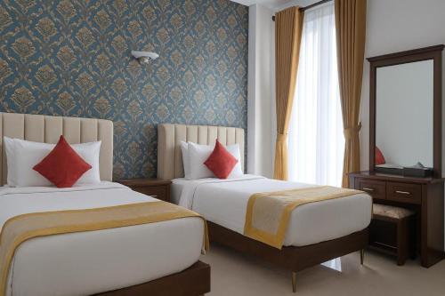 a hotel room with two beds with red pillows at Unique Towers Luxury Boutique Suites in Colombo