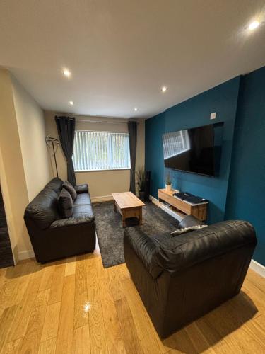 a living room with two leather couches and a flat screen tv at Balnakeil house