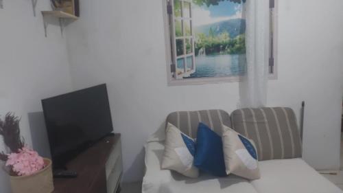 a living room with a couch and a flat screen tv at Casa Pousadinha Mel- QUARTOS E DORMITORIOS in Salvador