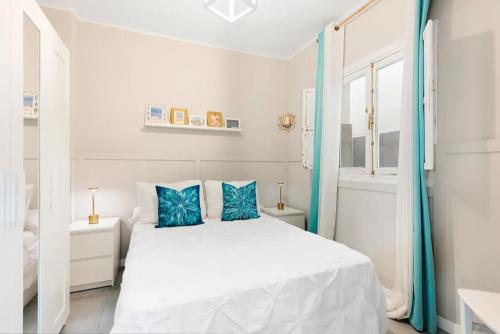 Un dormitorio blanco con una cama blanca con almohadas azules. en CASA playa 3dormitorios, en Málaga
