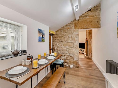 a dining room with a table and a stone wall at 2 Bed in Amble 91206 in Amble
