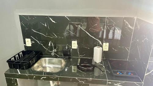 a kitchen with a sink and a black tiled wall at Alojamiento Paraíso del Parana in Carmen del Paraná