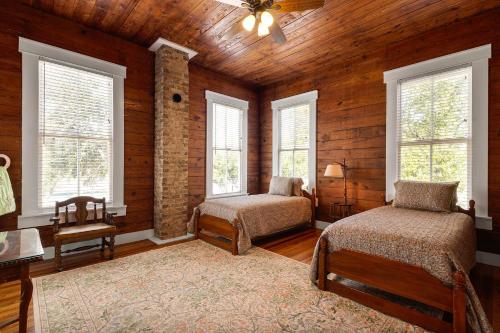 a bedroom with two beds in a room with wooden walls at The Bowie Grand - Historic Comfort in Seguin in Seguin