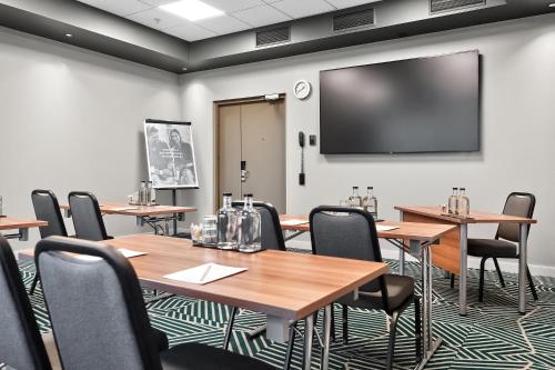 a conference room with tables and a large screen at Radisson Hotel Kaunas in Kaunas