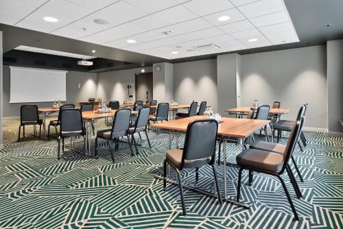 a conference room with tables and chairs and a projection screen at Radisson Hotel Kaunas in Kaunas