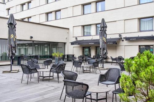a patio with chairs and umbrellas in front of a building at Radisson Hotel Kaunas in Kaunas