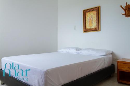 a white bed in a room with a picture on the wall at Atardeceres bloque A in Coveñas