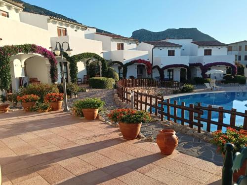 Un complejo con piscina y algunas plantas en macetas. en Hotel Resort Nuraghe Arvu, en Cala Gonone