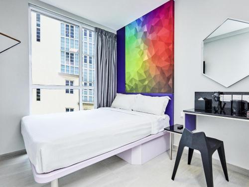 a bedroom with a bed and a colorful wall at ibis budget Singapore Ametrine in Singapore