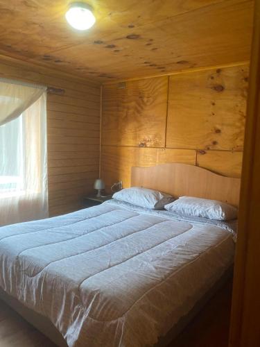a bedroom with a large bed with a wooden wall at Departamentos Schilling in Putemún