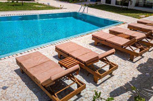 a swimming pool with two lounges and a swimming pool at The Edge in Bijilo