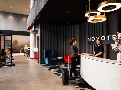 two people standing at a counter in a restaurant at Novotel Devonport in Devonport